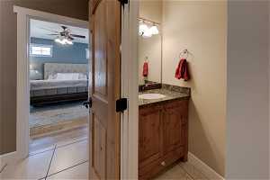 Bathroom featuring ceiling fan, vanity, mirror, and light tile floors