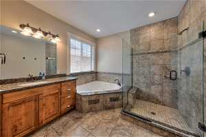 Bathroom featuring shower with separate bathtub, large vanity, mirror, and dark tile floors