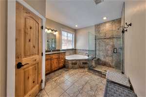 Bathroom featuring shower with separate bathtub, large vanity, mirror, and light tile floors