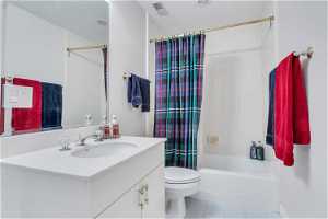 Full bathroom with a textured ceiling, mirror, light tile floors, oversized vanity, and shower / tub combo with curtain