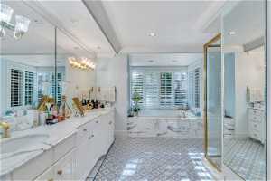 Bathroom with ornamental molding, mirror, a chandelier, separate shower and tub enclosures, light tile floors, and vanity