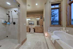 Bathroom featuring separate shower and tub, vanity with extensive cabinet space, mirror, and light tile floors