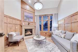 Cozy main-floor den/office with hardwood floors, a high ceiling and a fireplace