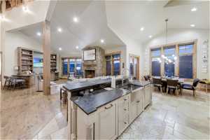 Kitchen featuring dark countertops, light tile flooring, wood floors, high vaulted ceiling