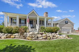 View of front of home featuring garage, a porch, and a front lawn