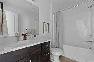 Full bathroom with shower / bath combo with shower curtain, vanity, mirror, and light hardwood floors