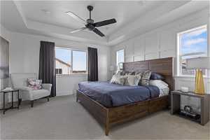 Carpeted bedroom with multiple windows, ceiling fan, and a raised ceiling