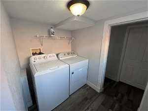 Washroom with dark laminate floors and washer and dryer