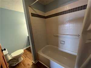 Bathroom with tiled shower / bath combo and light laminate floors