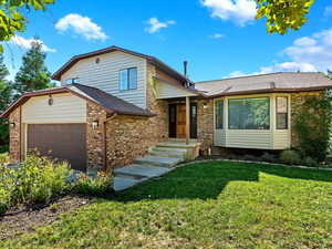 Split level home with garage and a front yard