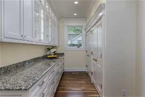 Kitchen featuring dark hardwood flooring, crown molding, and white cabinetry