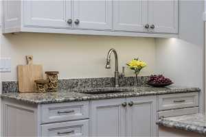 Kitchen featuring stone countertops and white cabinetry