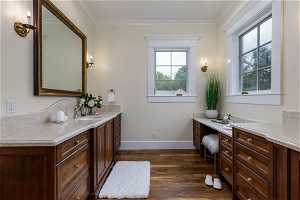 Bathroom with crown molding, dark hardwood flooring, oversized vanity, and mirror
