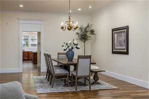 Dining area featuring a notable chandelier, light hardwood flooring, and crown molding