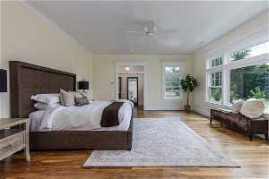 Bedroom featuring ceiling fan, light hardwood floors, and crown molding