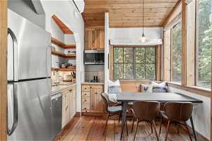 Kitchen featuring stainless steel appliances, pendant lighting, wooden ceiling, a wall mounted AC, light countertops, light hardwood flooring, and backsplash