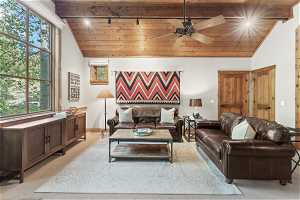 Living room with vaulted ceiling, light carpet, track lighting, ceiling fan, and wood ceiling