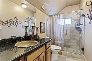 Bathroom featuring a textured ceiling, mirror, light tile floors, lofted ceiling, vanity, and a shower with curtain