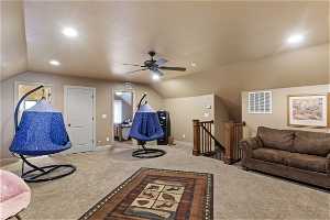 Living room featuring carpet floors, vaulted ceiling, and ceiling fan