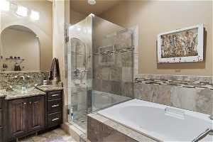 Bathroom with tile floors, vanity with extensive cabinet space, mirror, and shower with separate bathtub