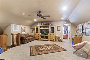 Carpeted living room featuring vaulted ceiling and ceiling fan