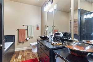 Full bathroom with hardwood flooring, double large sink vanity, mirror, and shower with separate bathtub