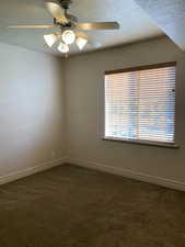 Carpeted spare room featuring a textured ceiling and ceiling fan