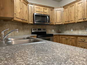 Kitchen with stainless steel appliances, backsplash, and brown cabinets