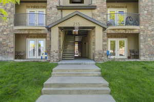 Doorway to property featuring balcony, a yard, and french doors