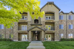 View of front of home with balcony, a front lawn, and french doors