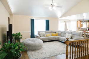 Living room featuring light hardwood flooring, a high ceiling, lofted ceiling, and ceiling fan