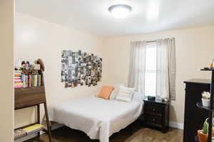 Hardwood floored bedroom featuring multiple windows