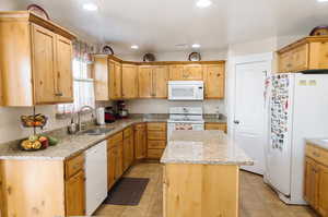 Kitchen with white appliances, light tile floors, and brown cabinets