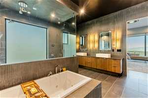 Bathroom featuring vanity, tile floors, mirror, tile walls, and shower with separate bathtub