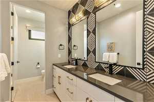 Bathroom with double vanity, mirror, and light tile floors