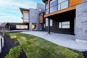 Rear view of house with a patio area, a yard, and a balcony