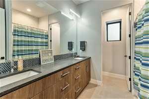Bathroom with light tile flooring, double sink vanity, and mirror