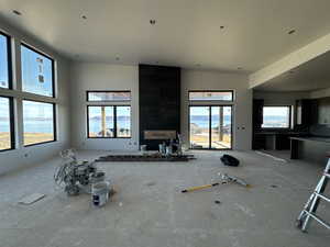 Unfurnished living room with a water view, vaulted ceiling, and a wealth of natural light