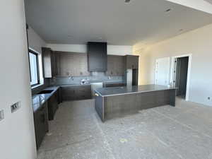 Kitchen featuring wall chimney exhaust hood and a spacious island