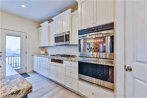 Kitchen featuring white cabinets, backsplash, stainless steel appliances,