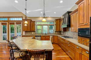 Kitchen with a kitchen island, a healthy amount of sunlight, and premium range hood