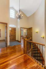 Entryway featuring vaulted ceiling high, a textured ceiling, carpet, and an inviting chandelier