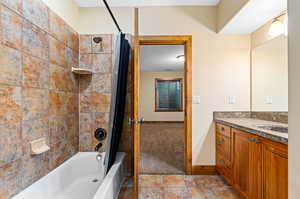 Bathroom featuring shower / bathtub combination with curtain, vanity, and tile floors