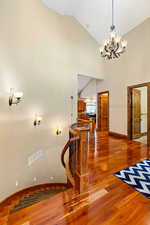 Stairs featuring a chandelier, dark hardwood flooring, and vaulted ceiling high