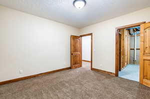 Unfurnished bedroom with light colored carpet and a textured ceiling