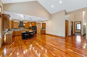 Kitchen featuring decorative light fixtures, a center island, hardwood floors, backsplash, and custom range hood