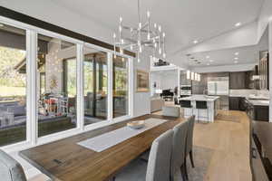 Dining area featuring high vaulted ceiling, an inviting chandelier, and light wood-type flooring