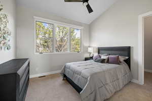 Carpeted bedroom featuring ceiling fan and lofted ceiling