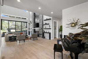 Living room with a high ceiling, light hardwood / wood-style floors, and a fireplace