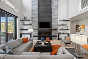 Living room featuring a stone fireplace, a towering ceiling, and hardwood / wood-style flooring